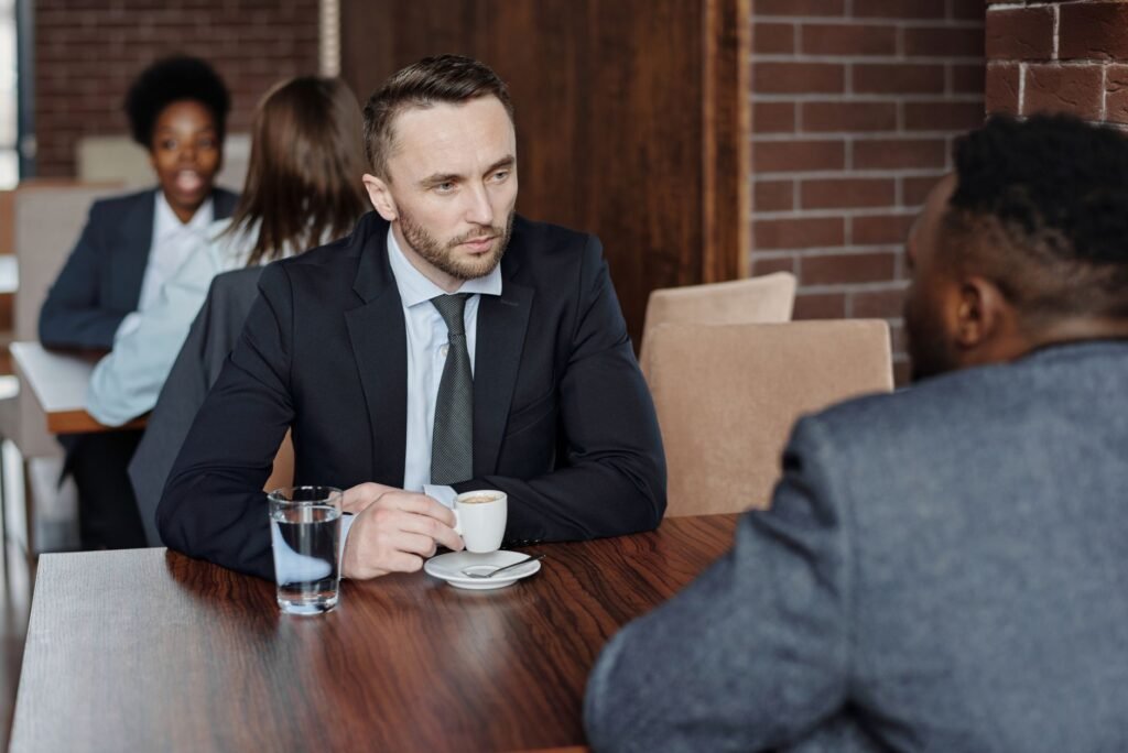 Two adults in relaxed conversation over coffee at a cafe table
