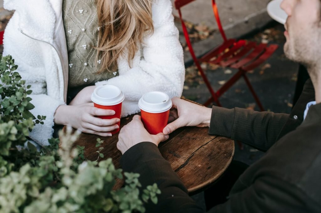 Two coffee cups, a smartphone and a notebook on a café table in natural daylight