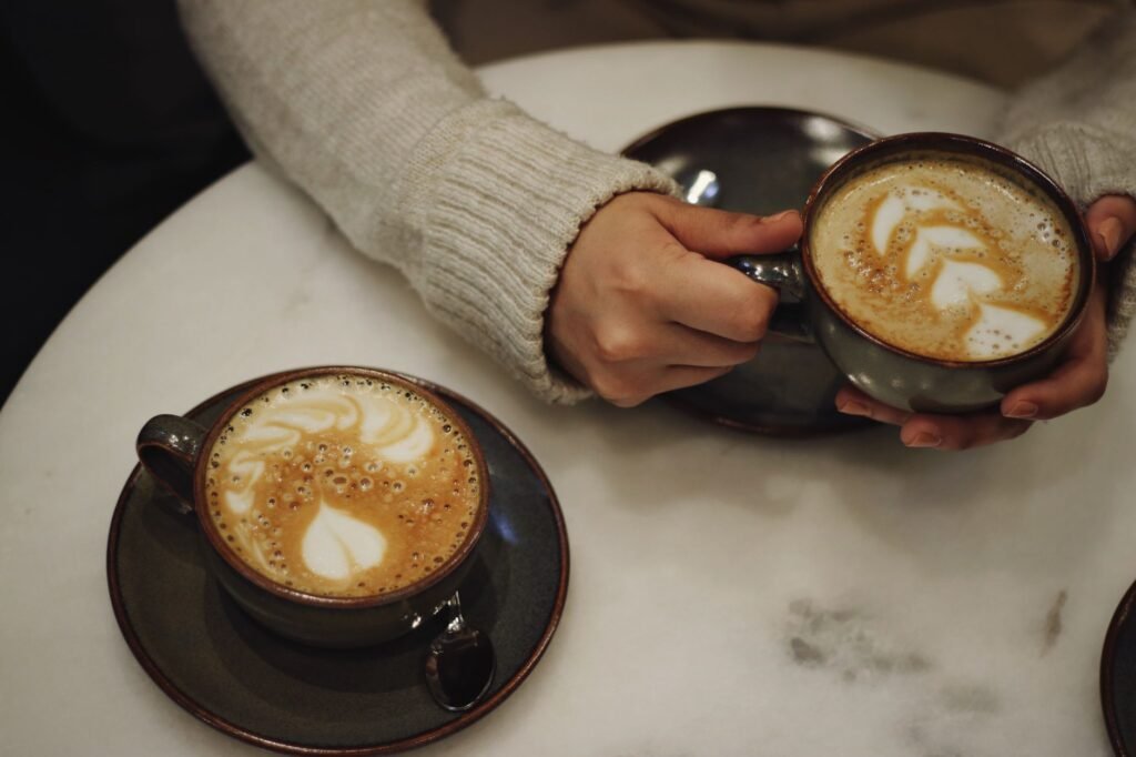 Two people holding coffee cups at a table