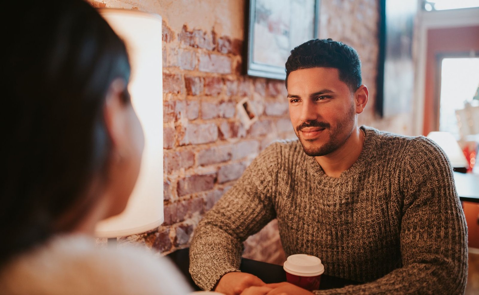 A man and woman having a friendly conversation over coffee in a café