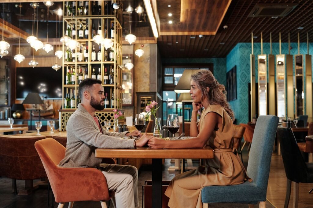 Two adults in relaxed conversation over dinner in a softly lit restaurant