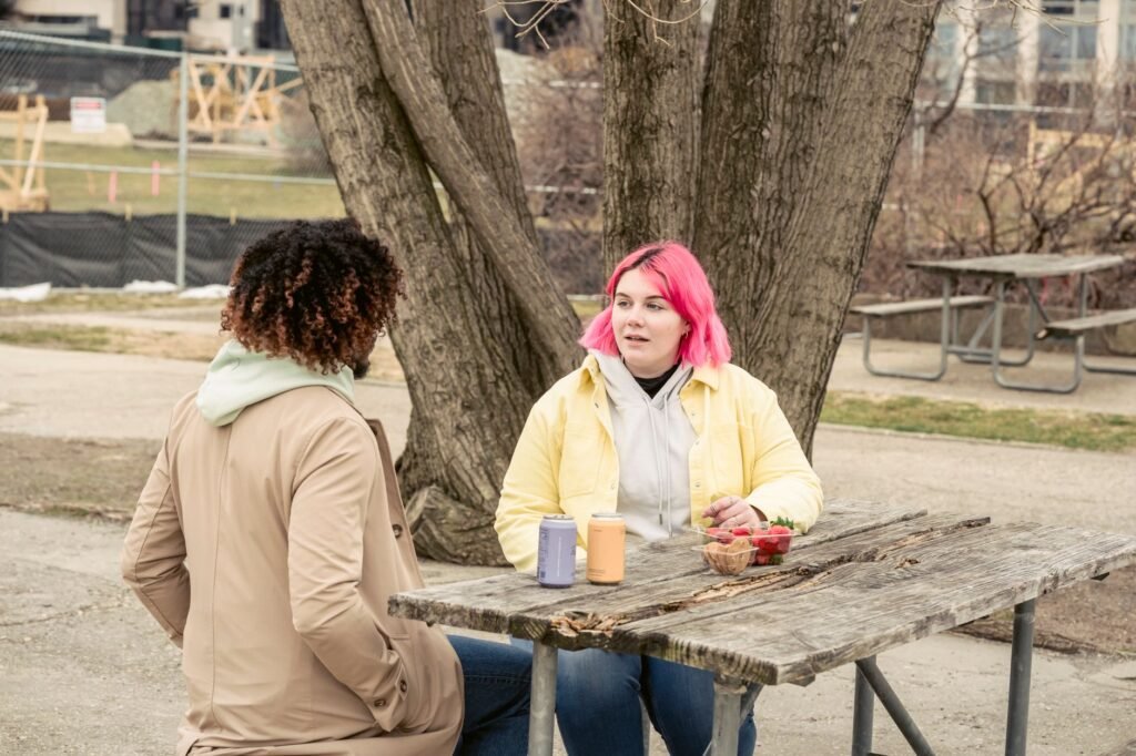 Two people in casual clothing in calm conversation at an outdoor cafe table