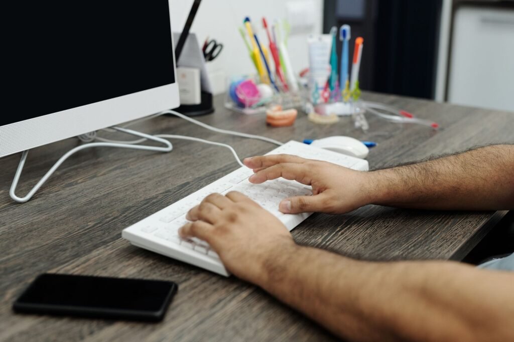 Person's hands typing a short message on a smartphone beside a notebook and coffee