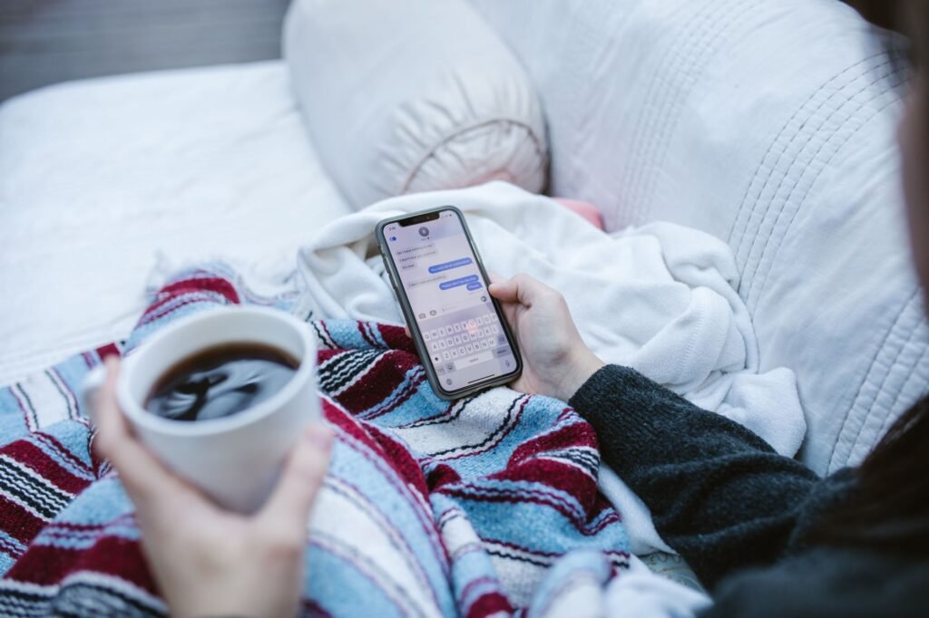 Hands using a smartphone beside a notebook and coffee in soft natural light